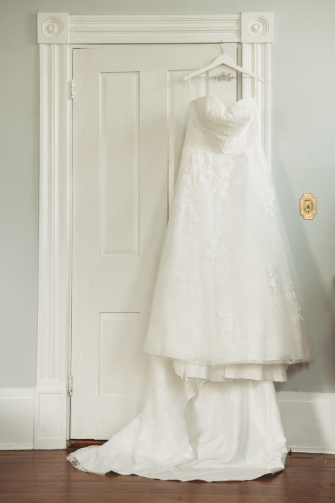 Bride's wedding dress hanging on the back of a door at Englund Estates venue  in Georgia 