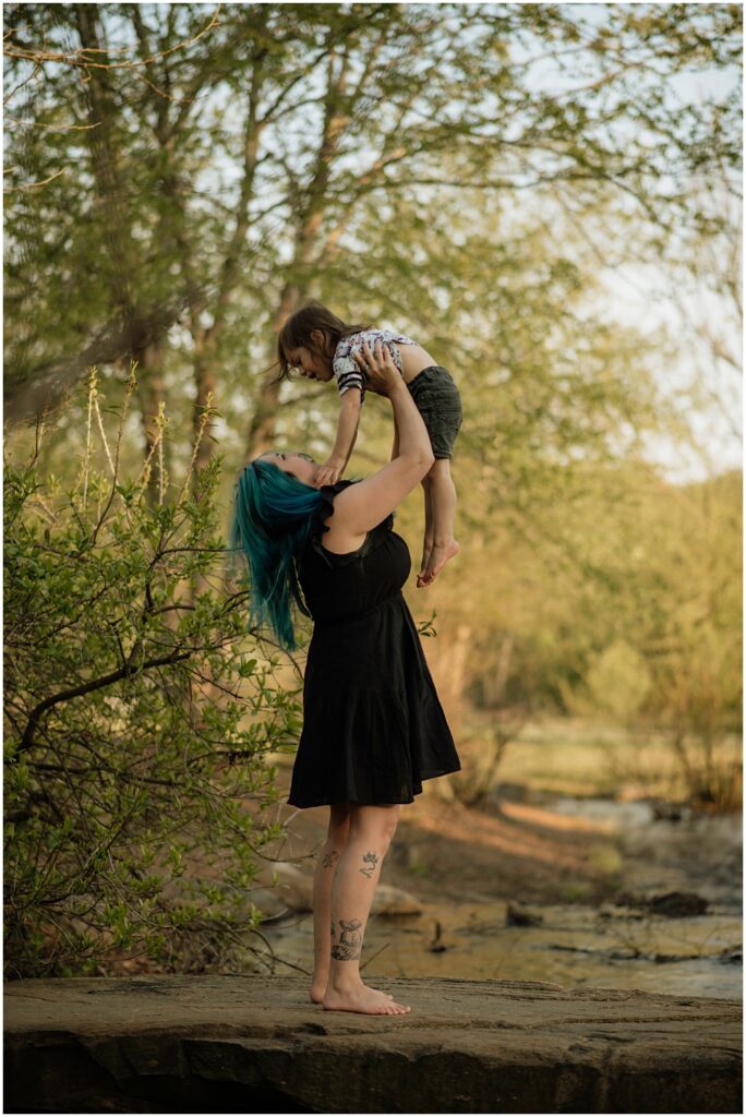 mom lifts toddler in air during their mommy and me session at Gerrard landing park for their Flowery Branch photographer 