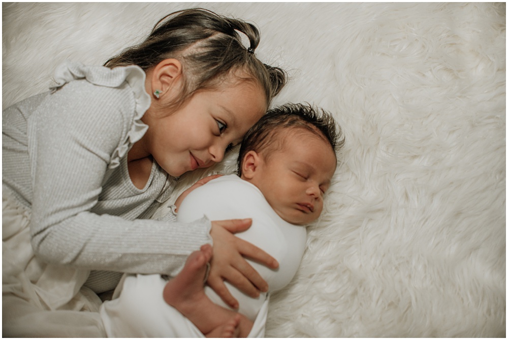 Flowery Branch photographer has a newborn baby in the studio. The newborn is surrounded by his siblings.